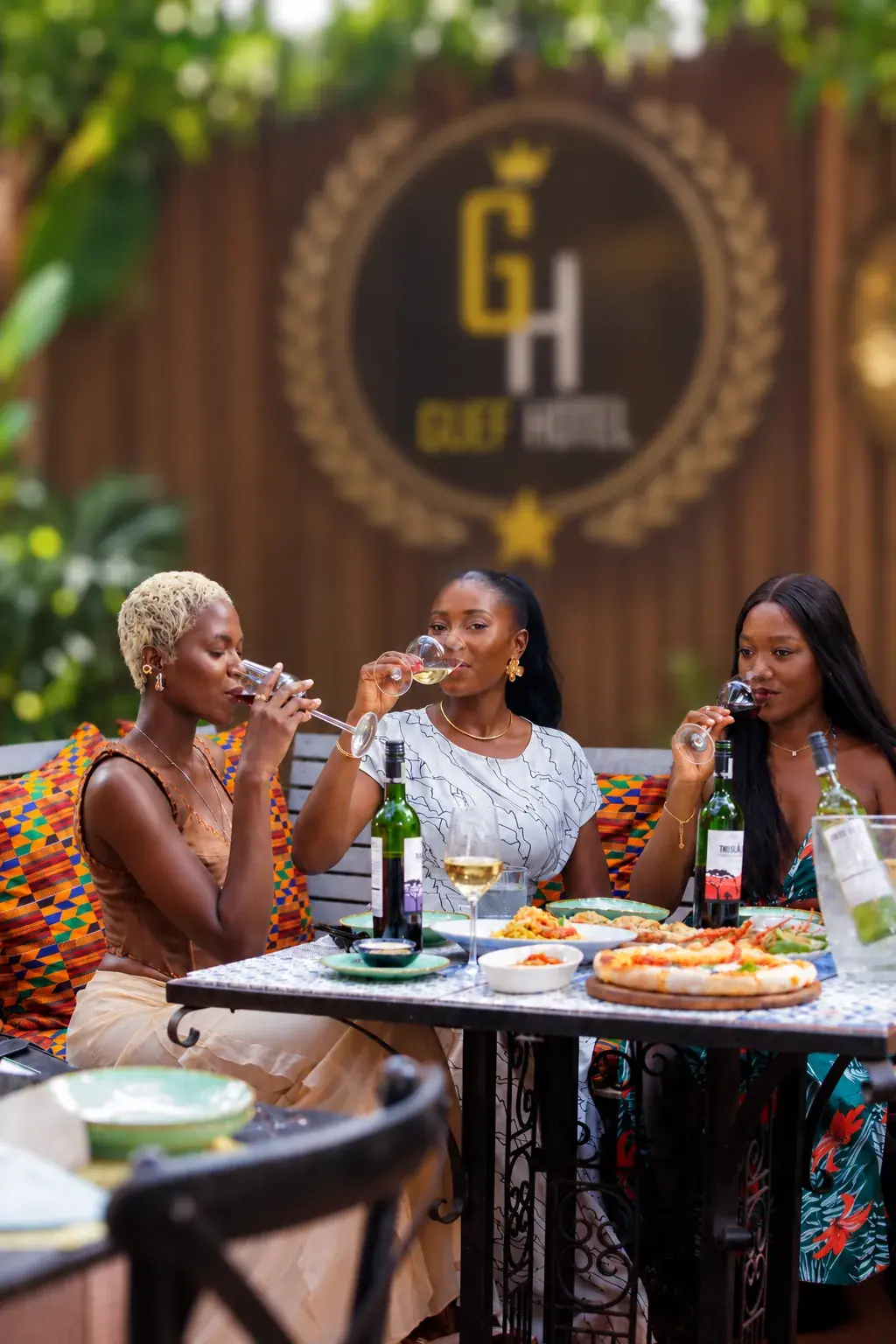 Clientes partageant un repas et un verre de vin en terrasse, sous le logo GUEF HOTEL